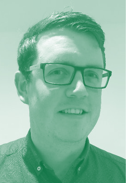 James with short dark hair and glasses wearing a dark collared shirt against a plain light background.